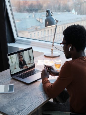 Rear view of businessman talking to his colleague on laptop during online meeting